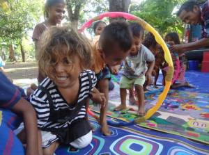 Community children play with the hula hoop tunnel after reading.